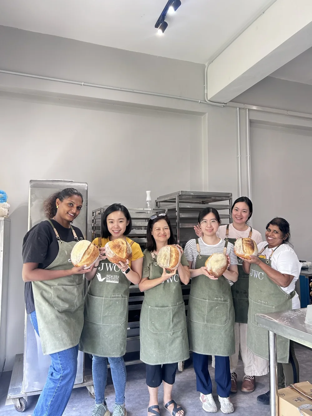 Real BWC learners holding sourdough loaves after classroom practice
